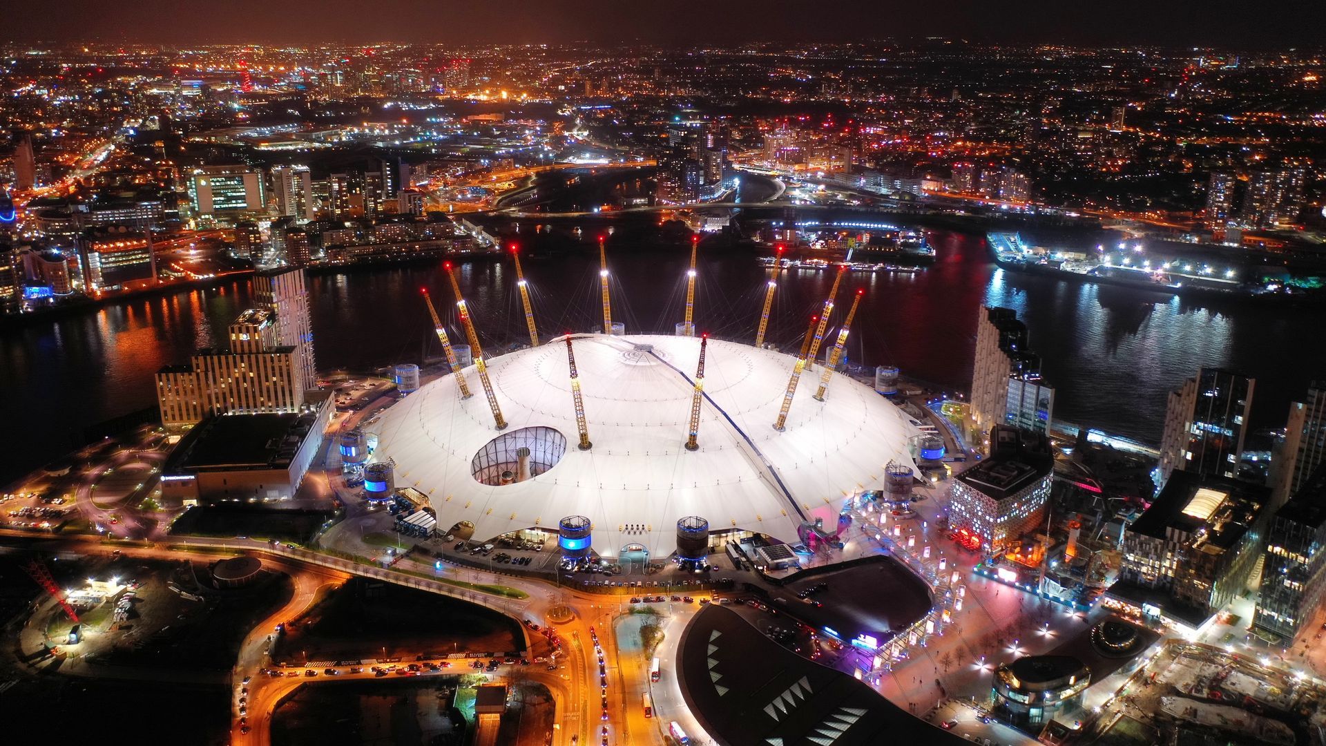 An aerial view of a stadium at night with a city in the background.