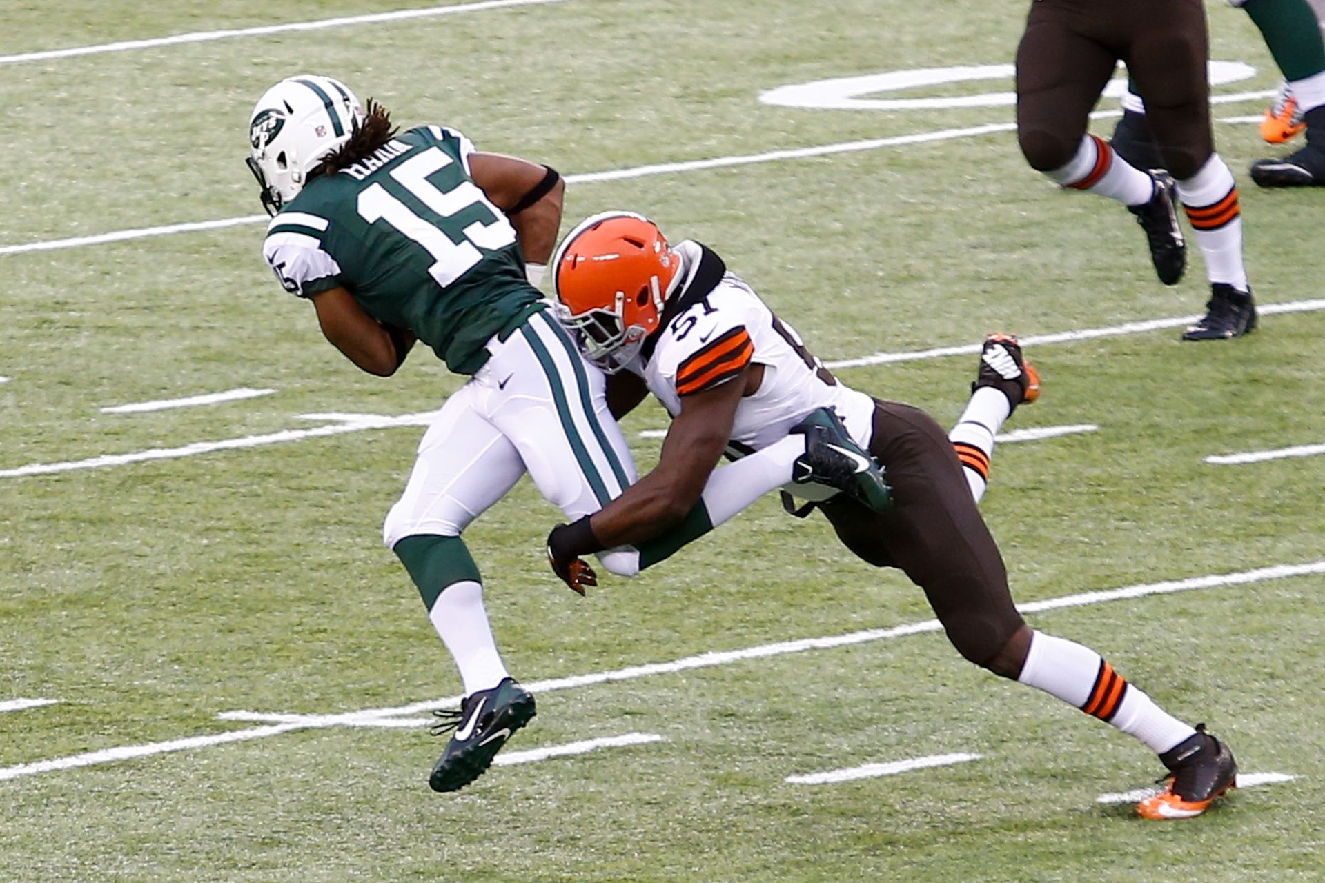 A football player with the number 15 on his jersey is tackled by another player