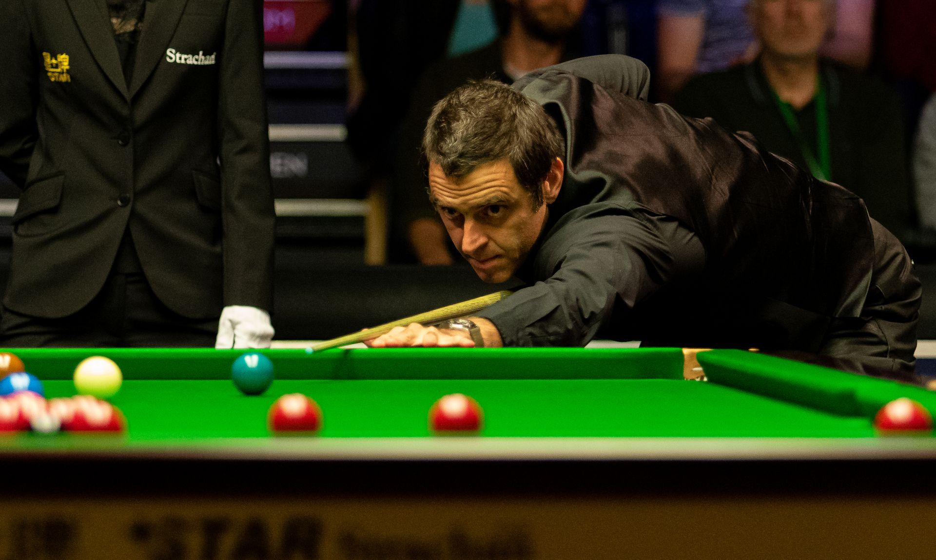 A man is playing snooker on a pool table.