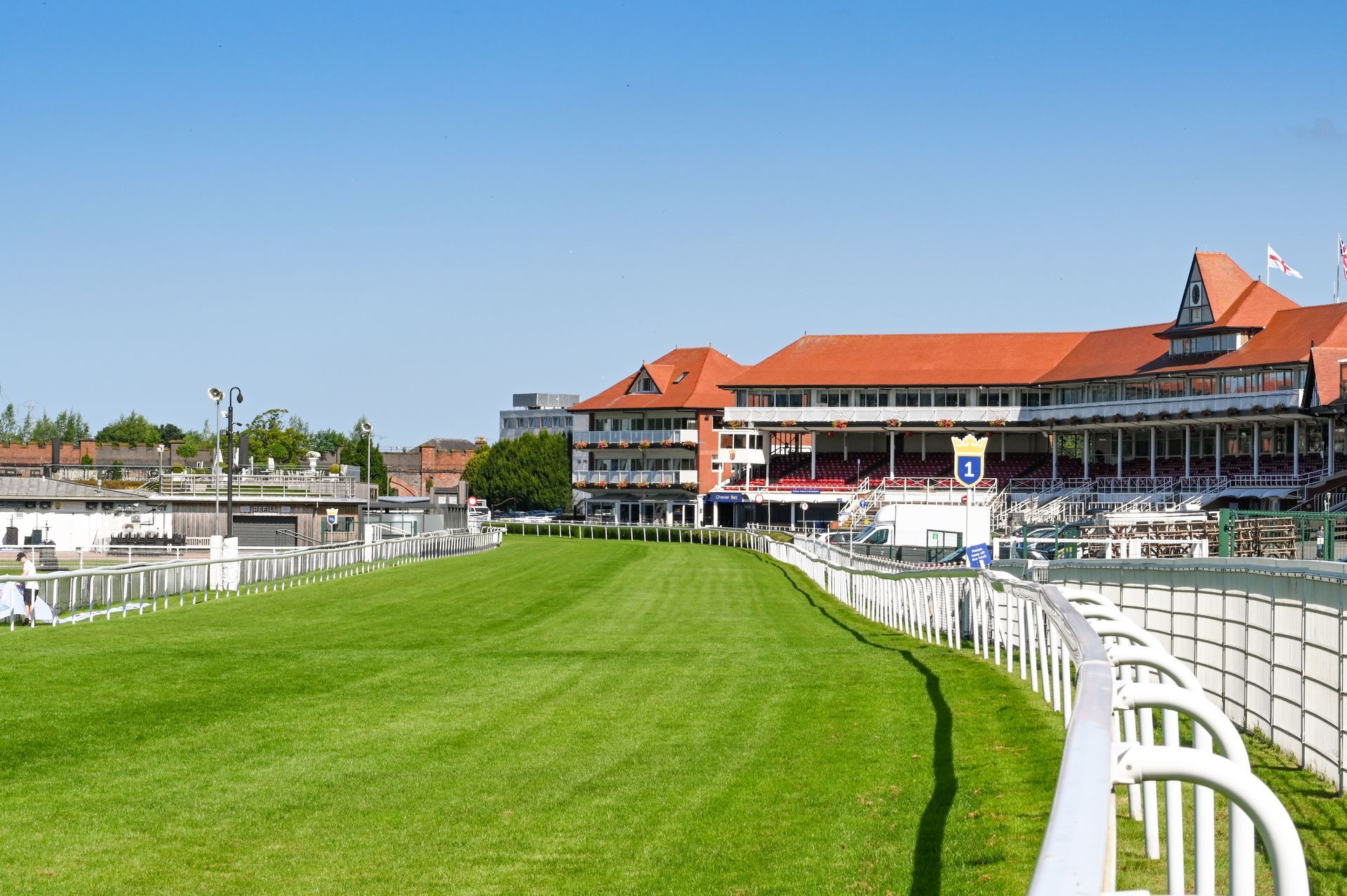 A race track with a large building in the background and a fence in the foreground.
