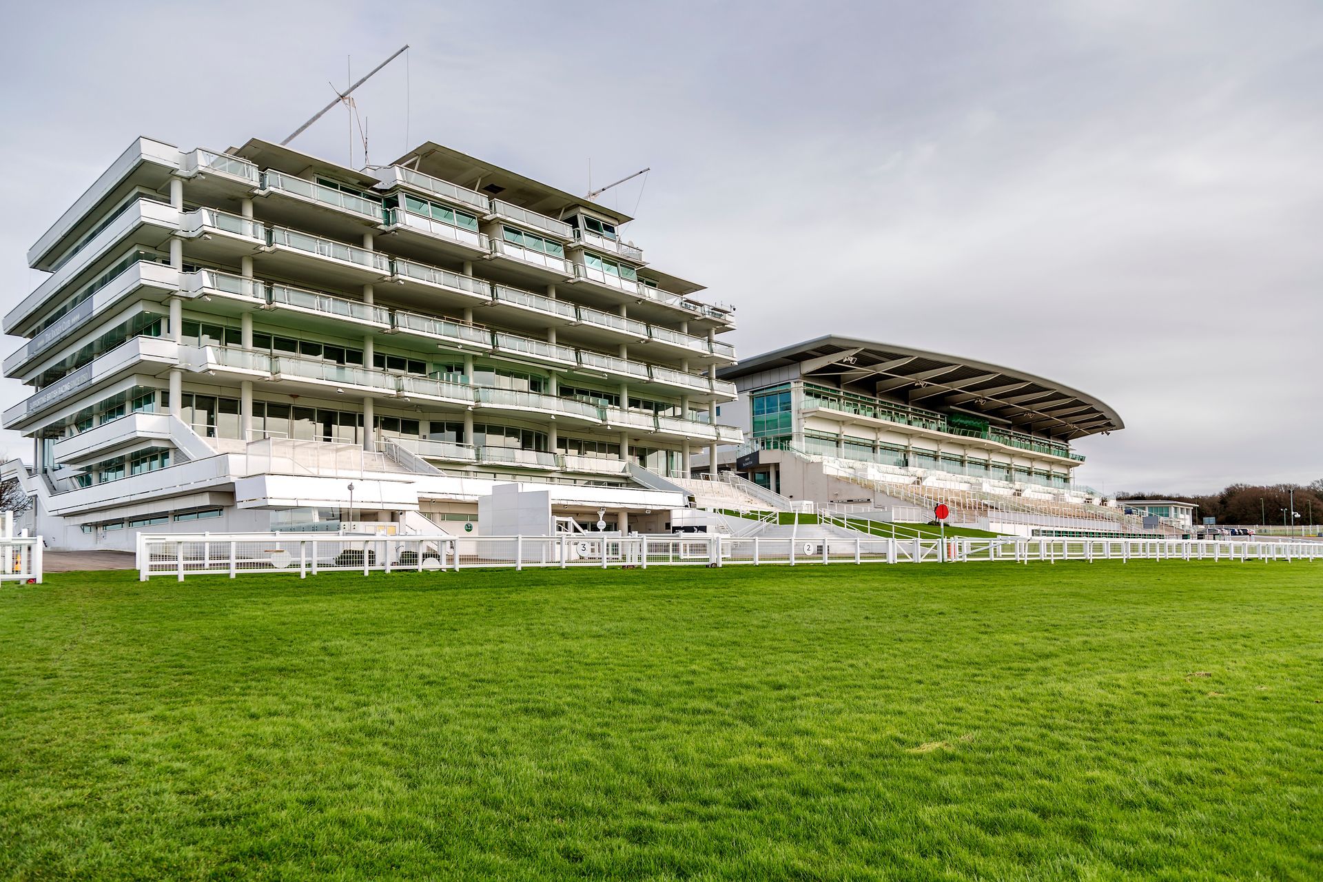 A large building with a lot of balconies is sitting on top of a lush green field.