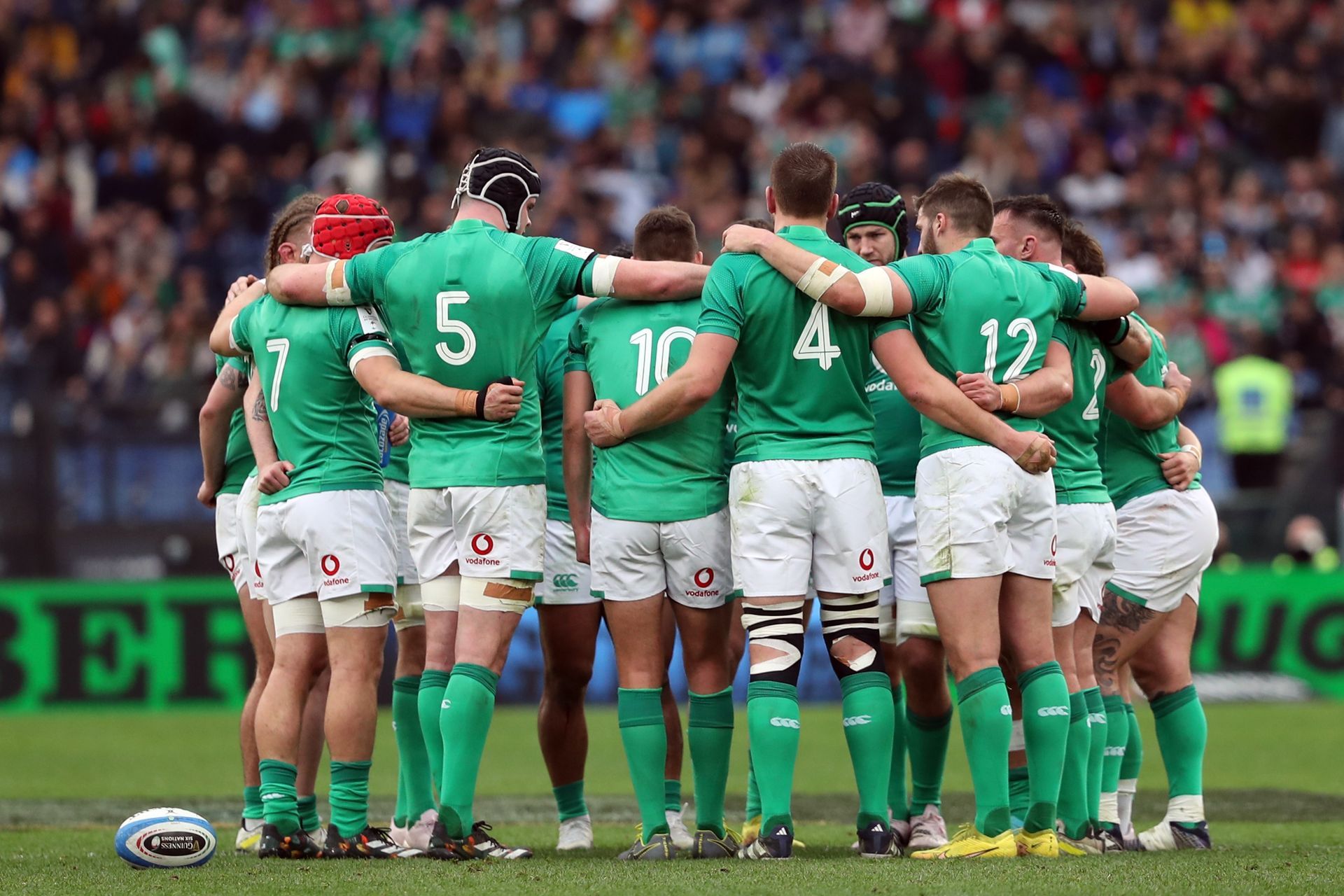 A group of rugby players are huddled together on the field.