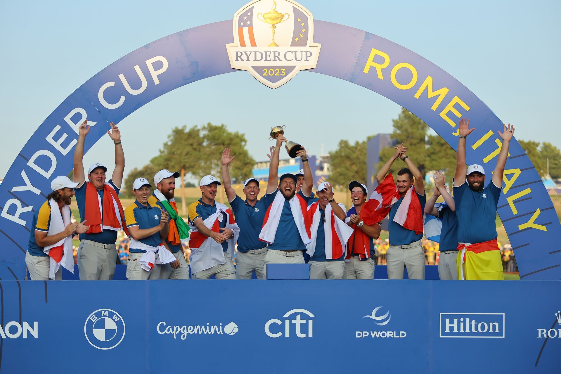 A group of people standing in front of a sign that says ryder cup rome italy