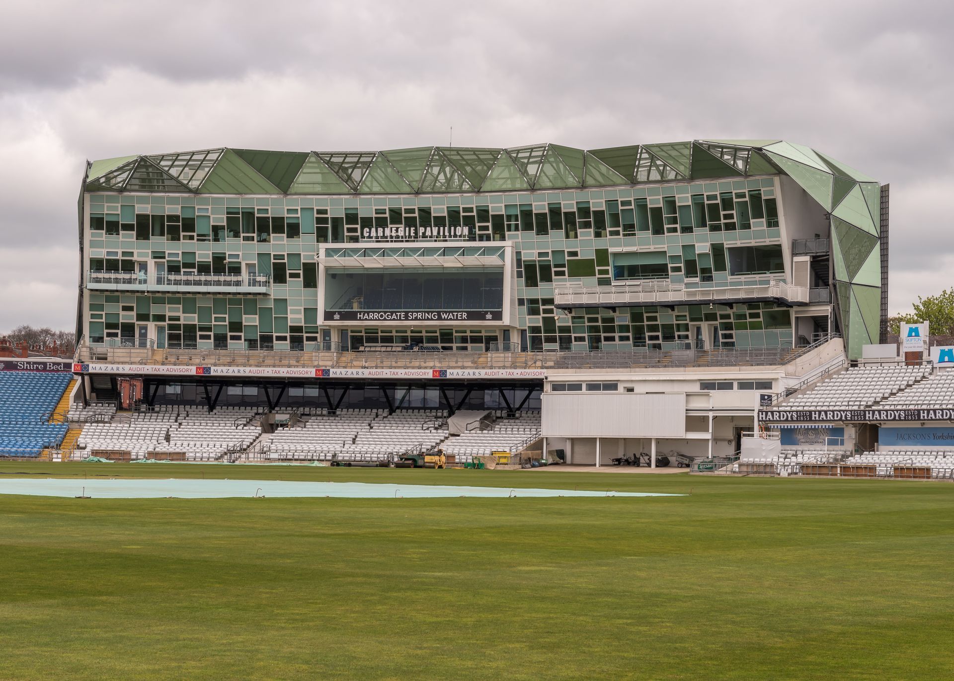 A large building with a lot of windows is sitting on top of a lush green field.