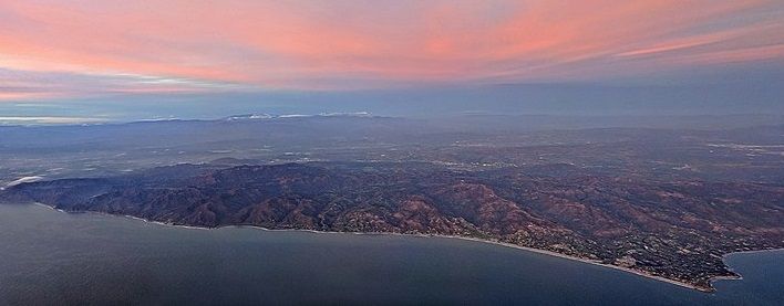 An aerial view of a city and a body of water at sunset.