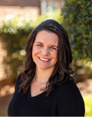 A woman in a black shirt is smiling for the camera.