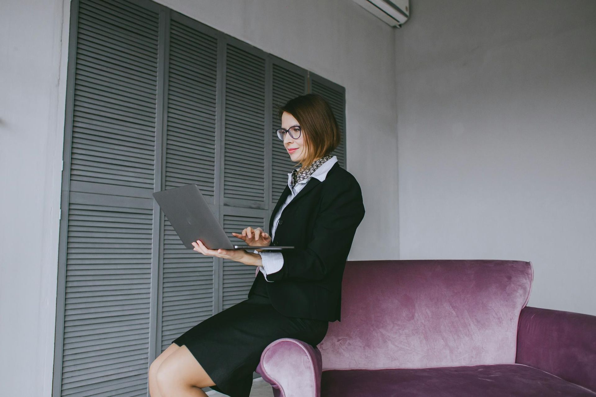 A woman in a suit working on a laptop, illustrating leadership vision through strategic writing