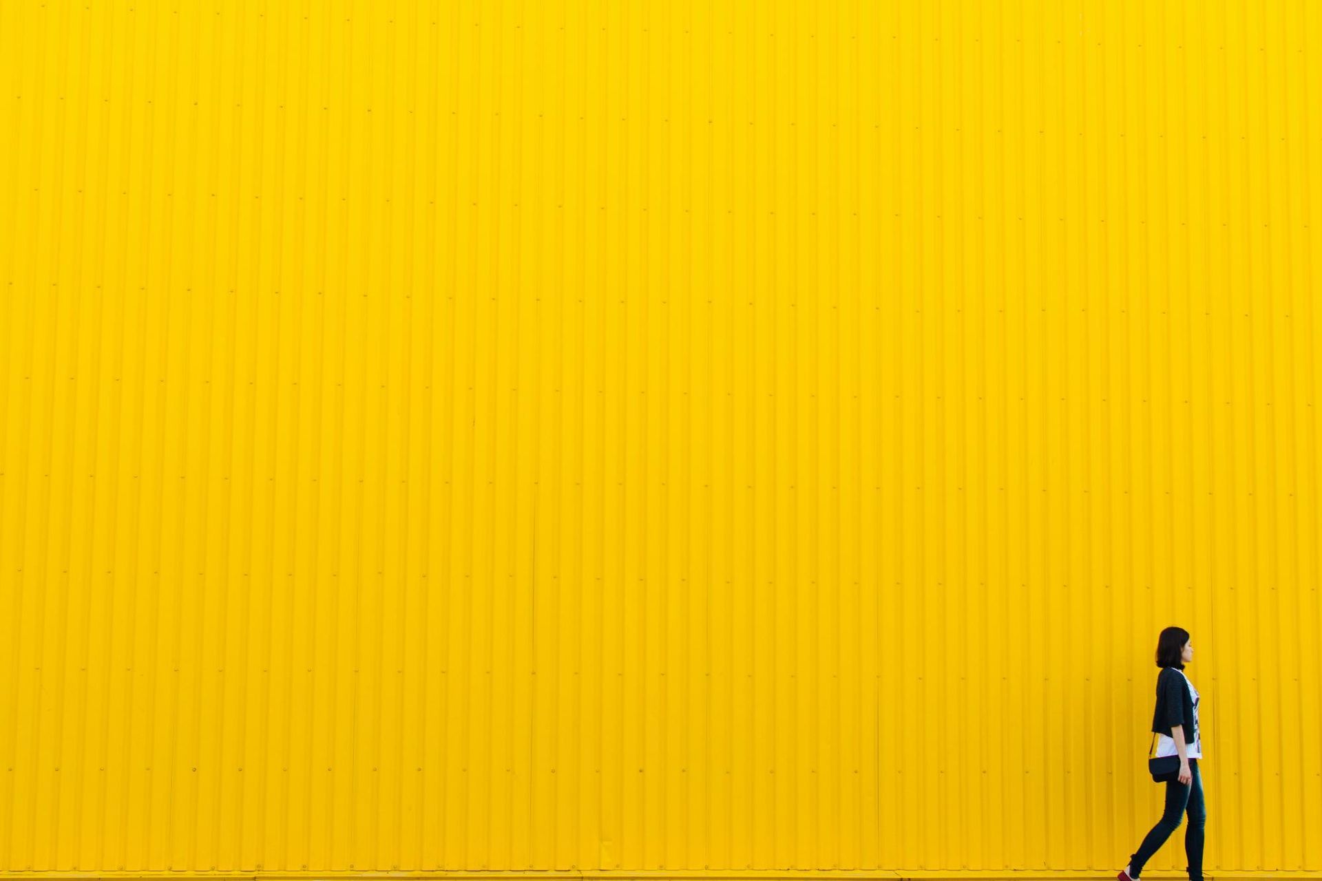 A woman walking in front a yellow wall