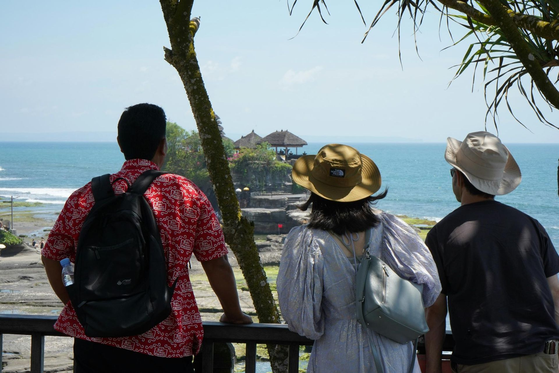 Three people standing at a viewpoint, looking out at the ocean.