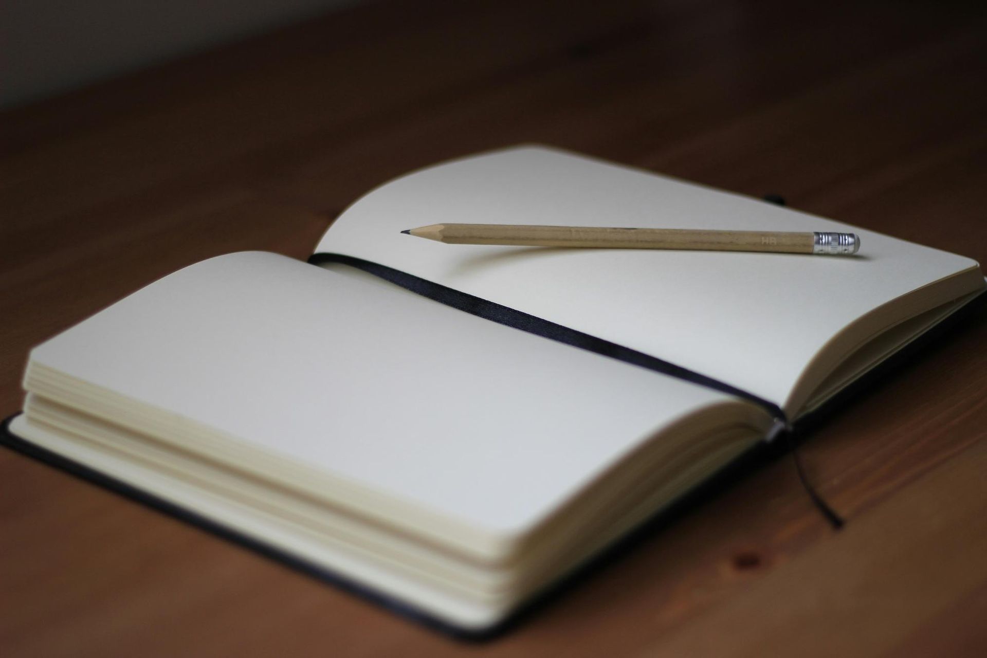 A pencil resting on an empty page of a notebook.