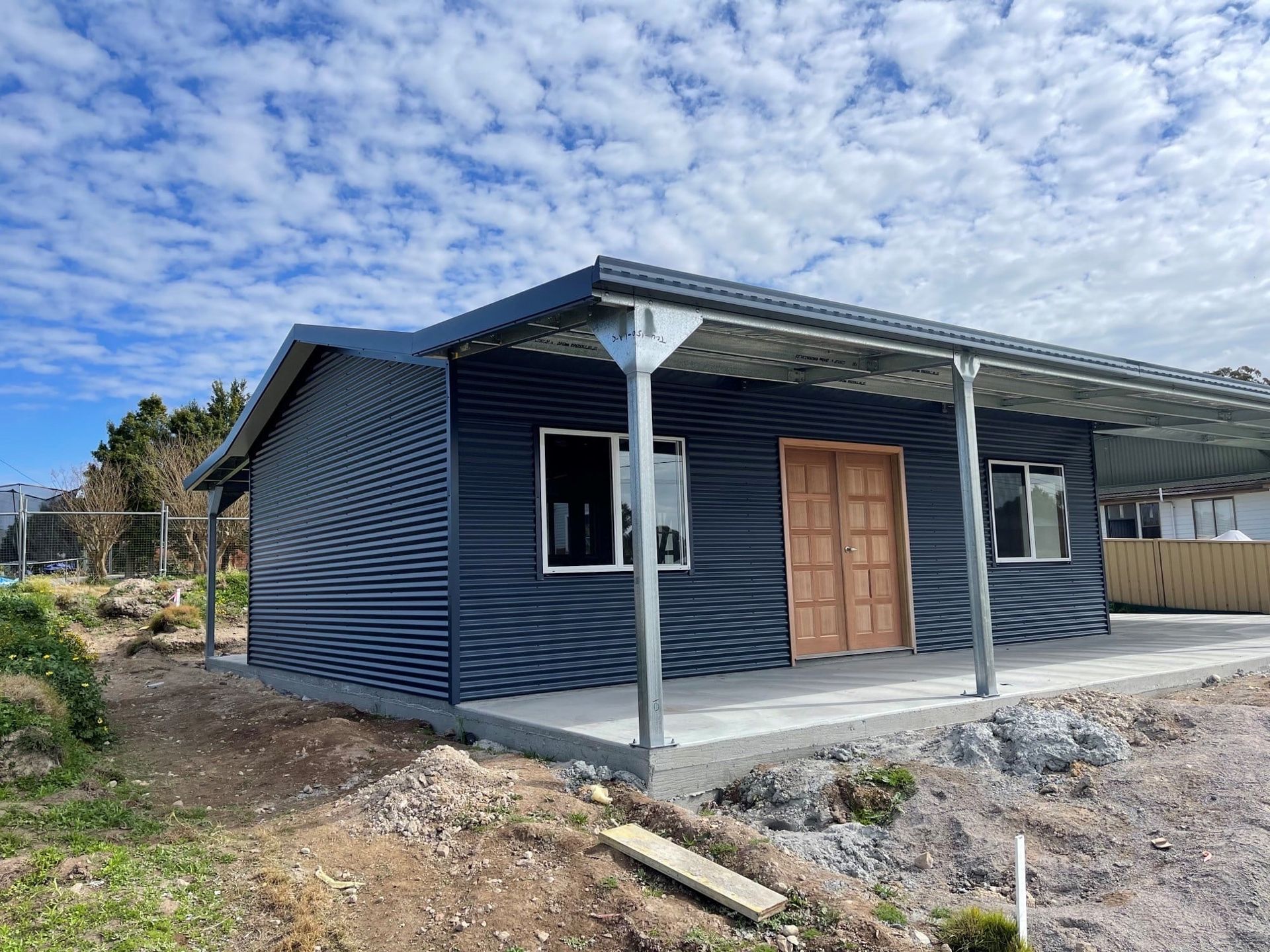 A small house with a porch and a roof is being built.