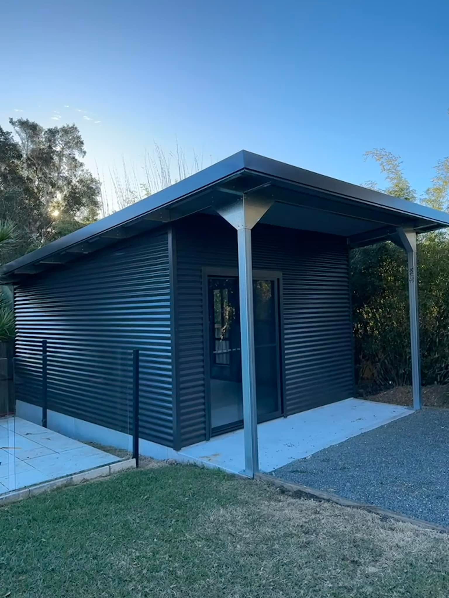 A small black building with a covered porch in the backyard.