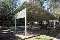 A covered area with picnic tables and trees in the background.