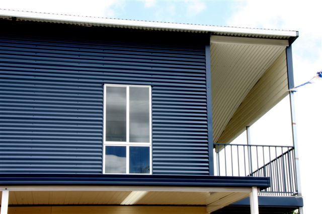 A blue house with a balcony and a window