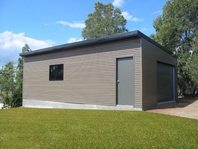 A small building with a door and a window is sitting on top of a lush green field.