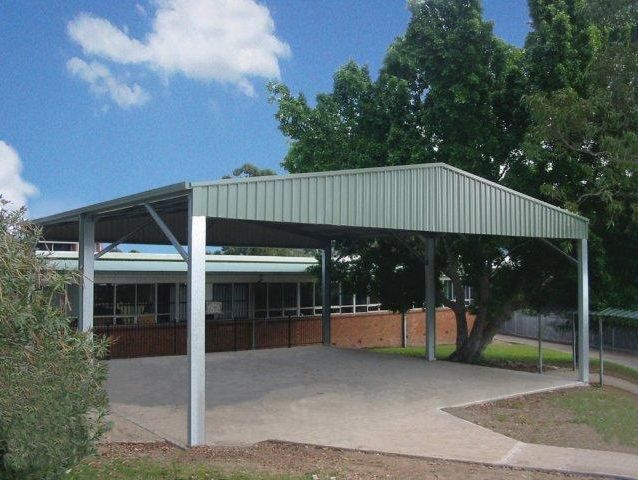 A carport with a green roof in front of a building