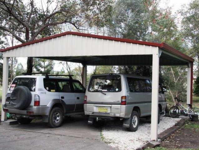 Two cars are parked under a carport and one has a license plate that says ' nz ' on it