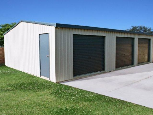 A garage with three garage doors and a concrete driveway
