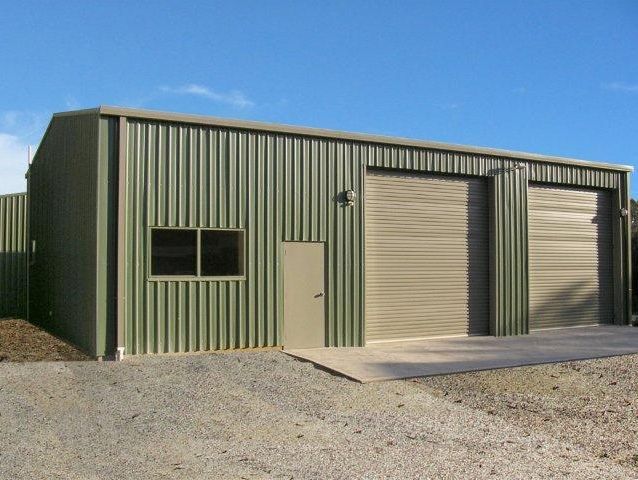 A green building with two garage doors and two windows