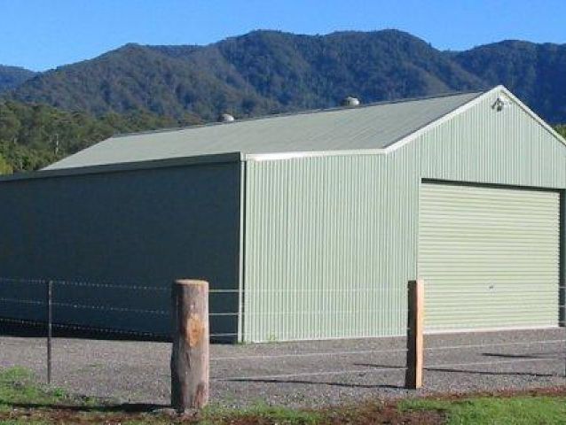 A green garage with mountains in the background