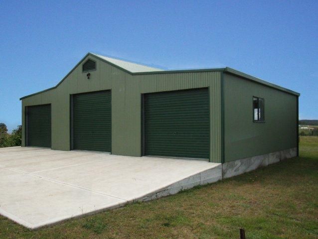 A green garage with three garage doors and a window