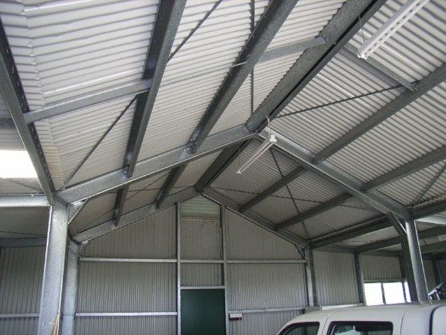 A white truck is parked inside of a metal building