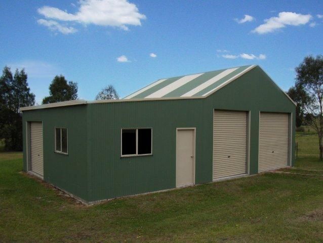 A green building with a white roof is in the middle of a grassy field