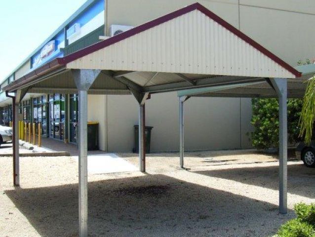 A white carport with a red roof in front of a building