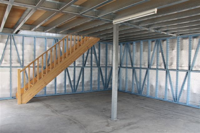 An empty room with a wooden staircase leading up to the second floor