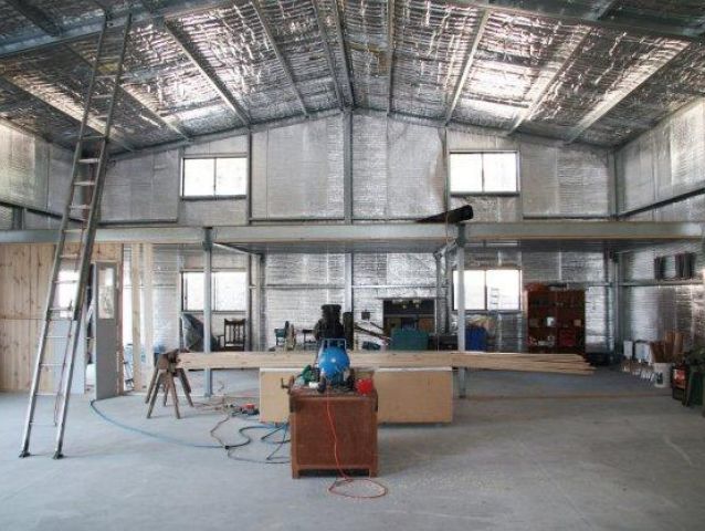 A large room with a ladder, plywood and a table in it