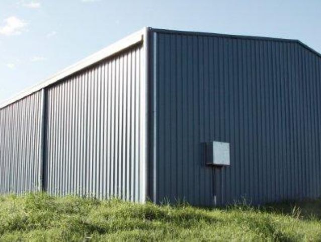 A large metal building is sitting on top of a grassy hill.