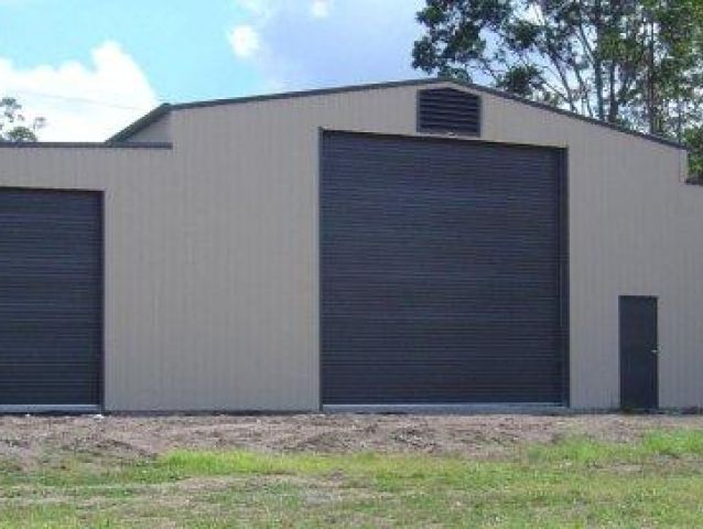 A large building with two black garage doors and a black door