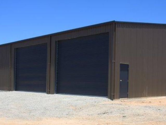A large metal building with three garage doors and a door.
