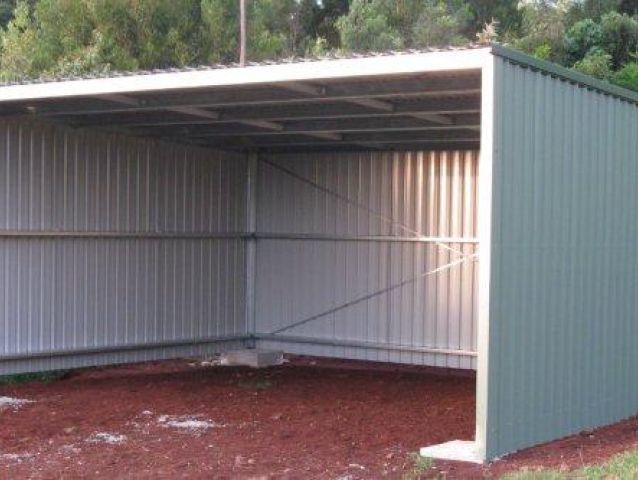 A shed with a white roof is sitting on top of a pile of dirt.