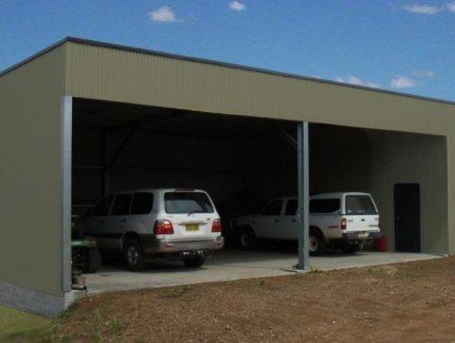 Two cars are parked under a canopy in a garage