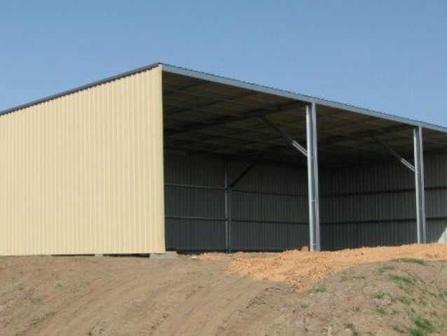 A color cream large building is sitting on top of a dirt hill