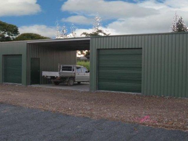 A truck is parked in a garage with green doors.