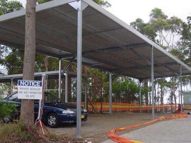 A blue car is parked under a notice sign