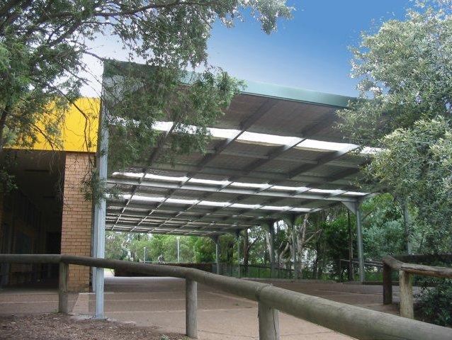 A carport with a wooden fence and trees in the background