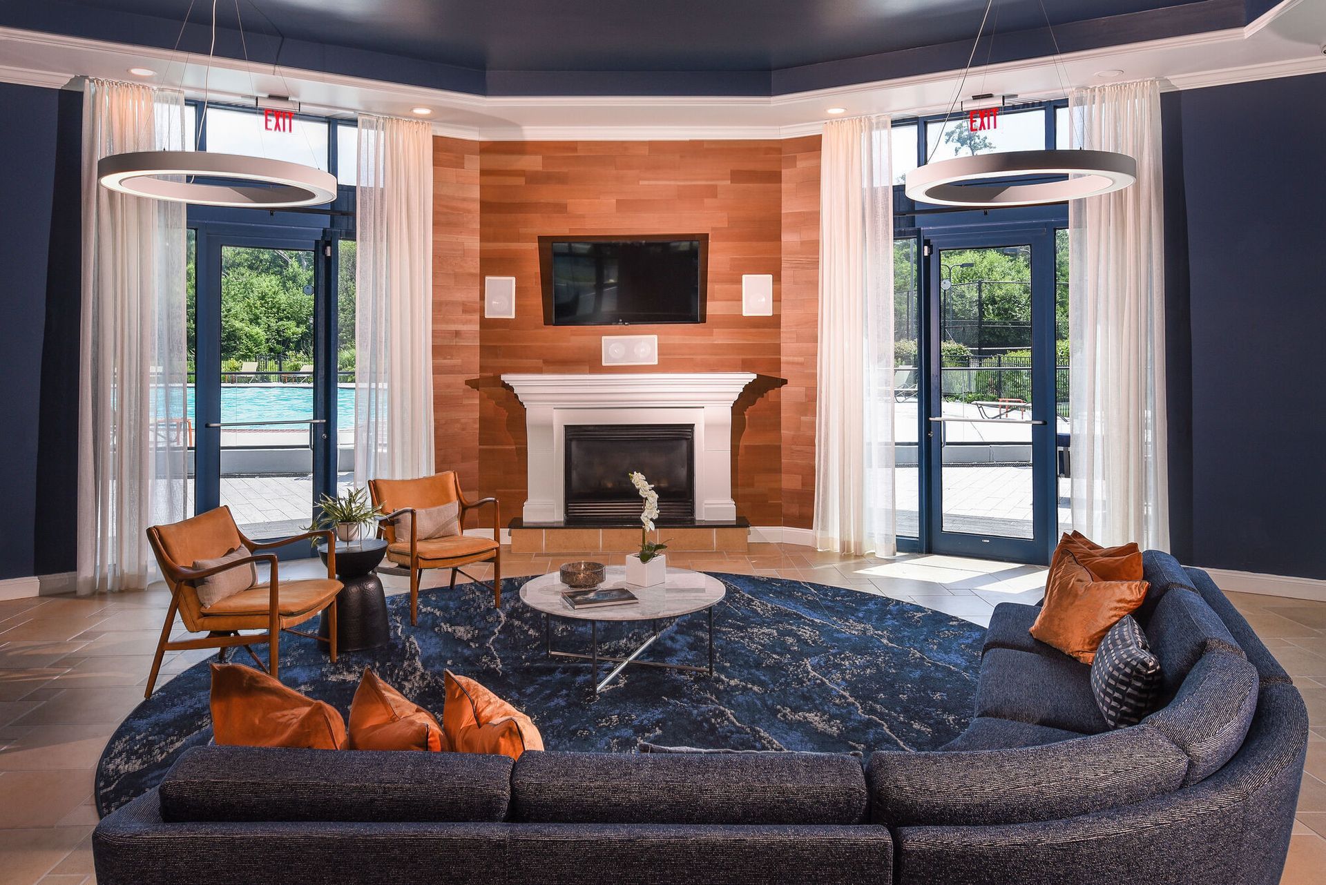 Interior communal lounge with a fireplace, blue walls, and seating; glass doors to outdoor pool.