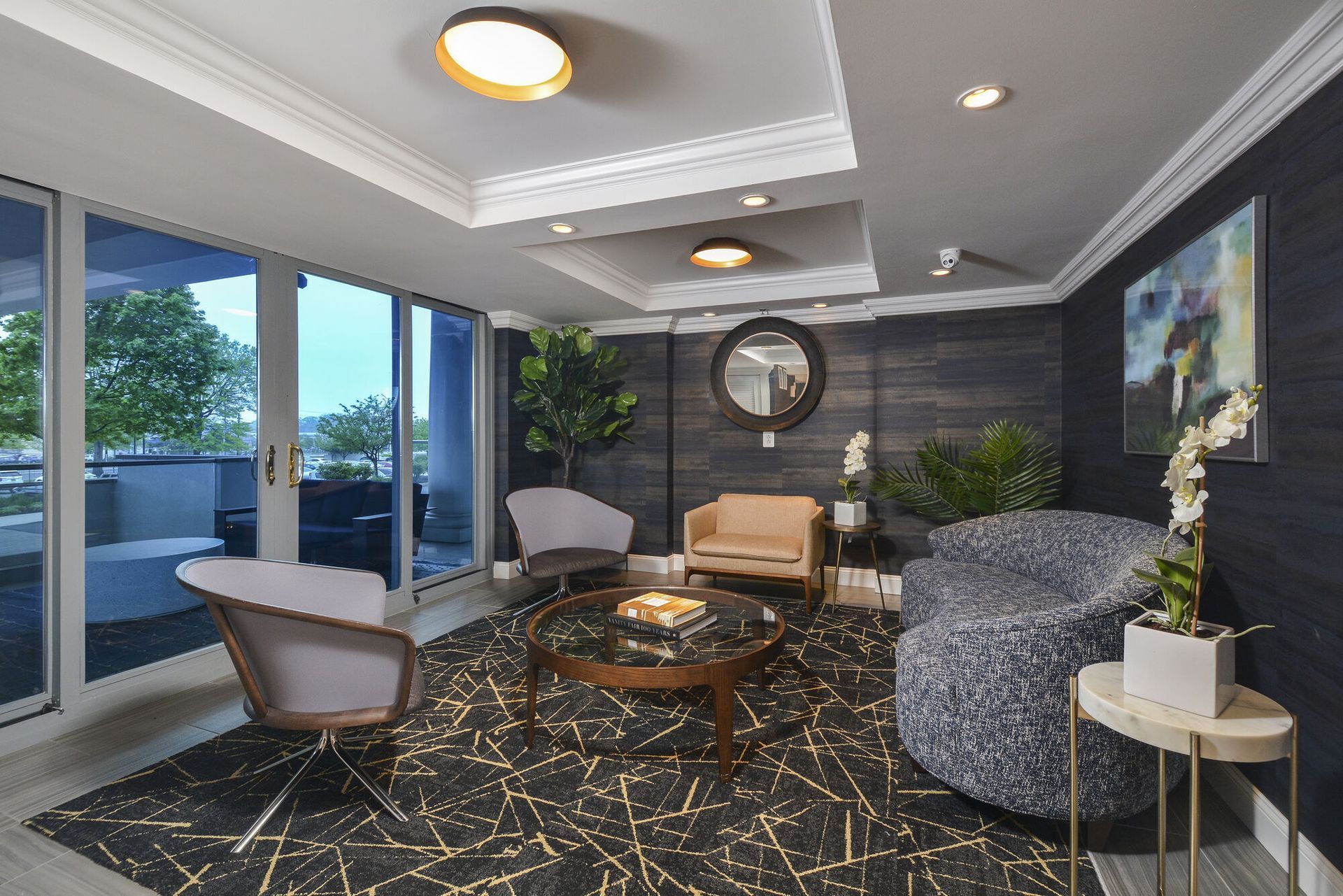 Interior community lounge with contemporary seating, a coffee table, and large glass doors opening to a balcony.