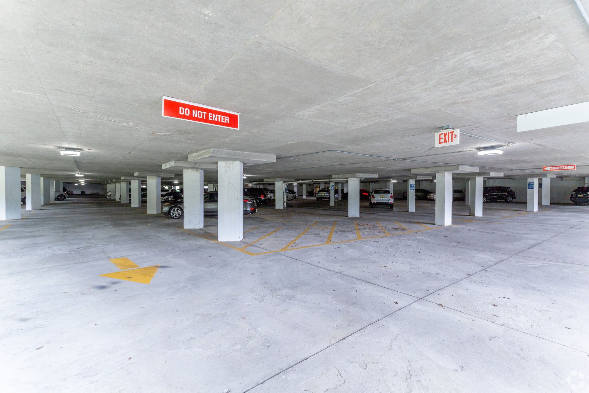 Underground parking garage with concrete pillars and parked cars.