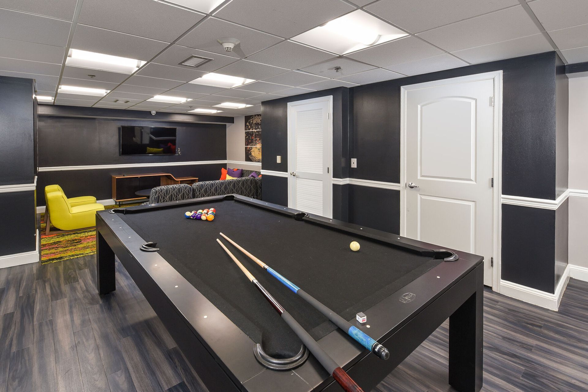 Indoor community recreation room with a pool table, seating, and a wall-mounted TV.