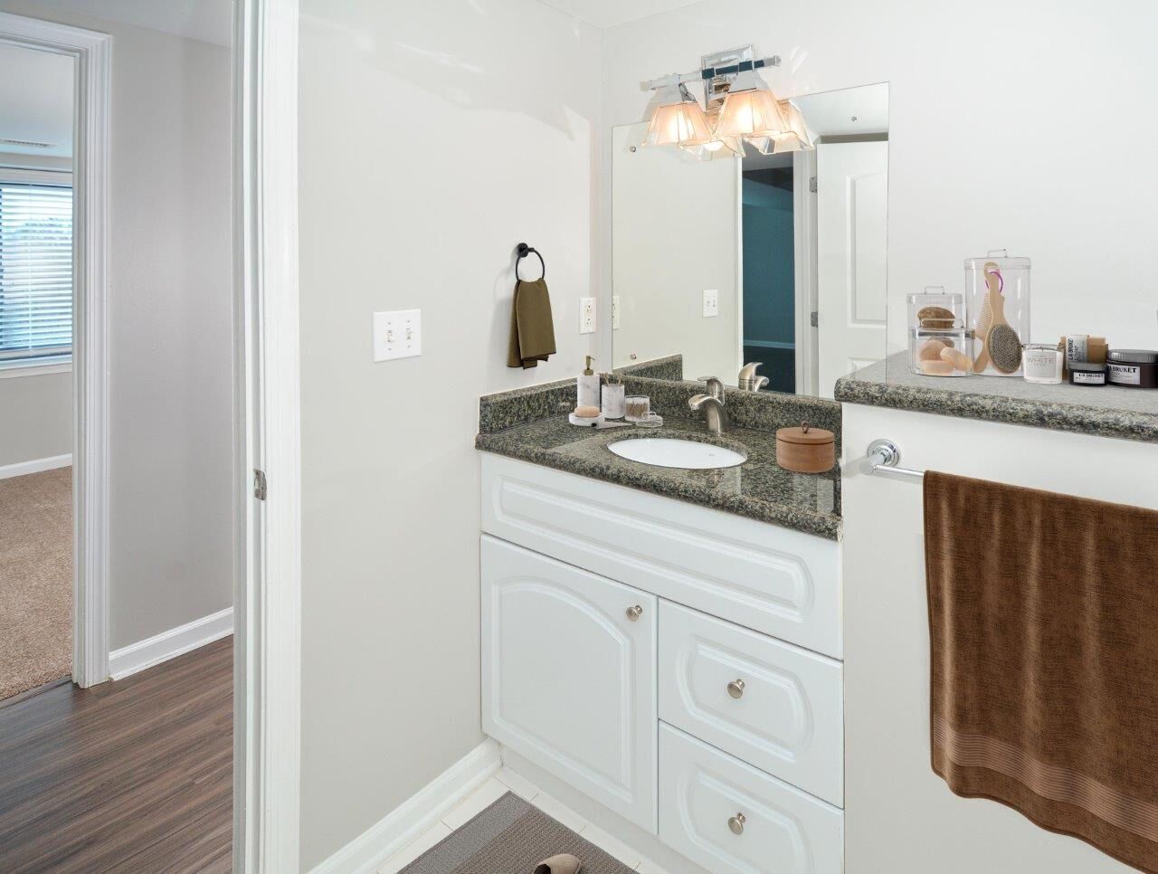 Bathroom vanity with granite countertop, sink, mirror, and towel rack.