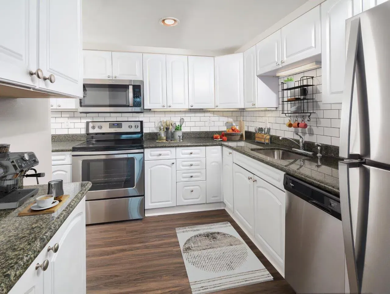 U-shaped kitchen with white raised-panel cabinets, granite countertops, and stainless steel appliances.