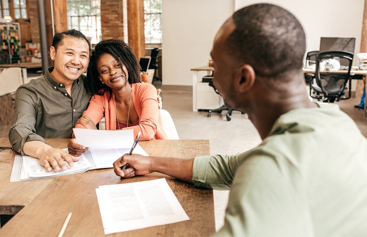 couple sitting across from man while all reviewing paperwork