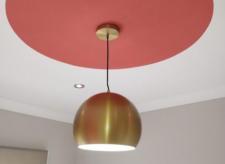 Decorative gold hanging light fitting installed in bedroom with red circular accent on ceiling