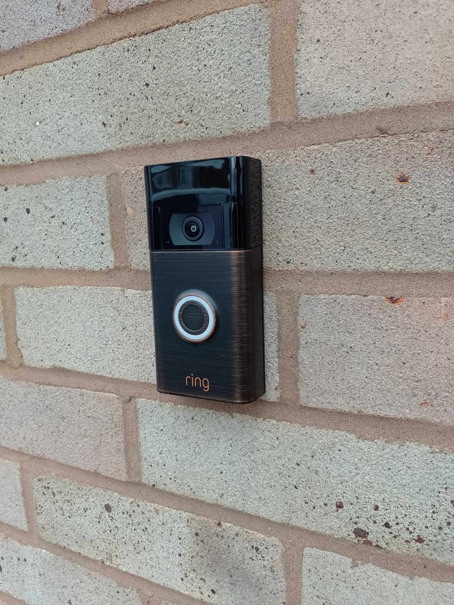 Ring wired door bell installed on a light coloured brick wall