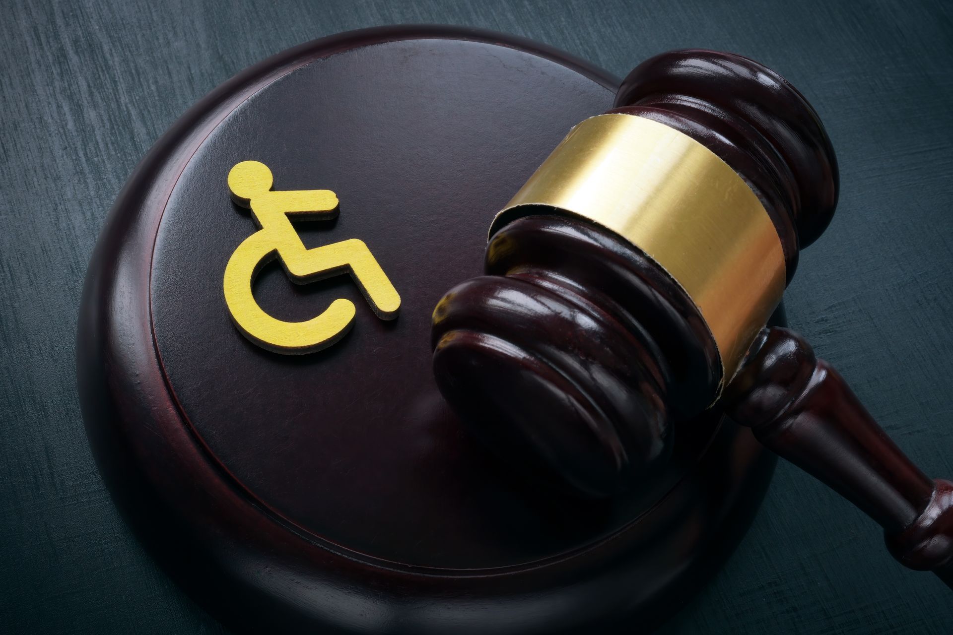 A judge’s gavel rests beside a disability symbol on a wooden block representing legal support. A judge’s gavel rests beside a disability symbol on a wooden block representing legal support.