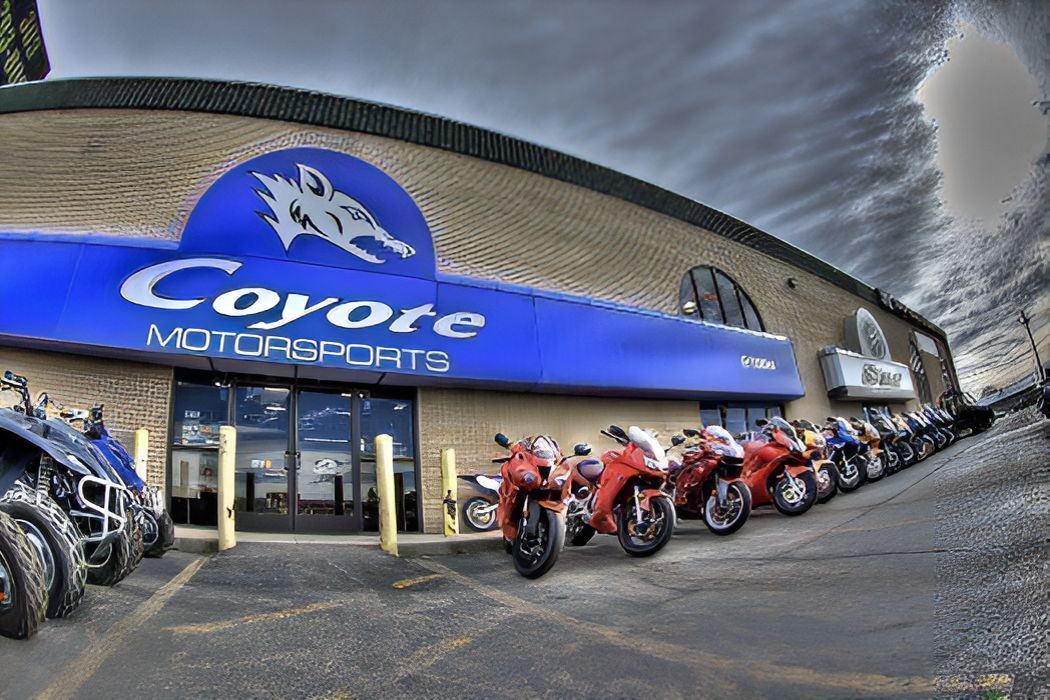 A row of motorcycles are parked in front of a coyote motorsports store